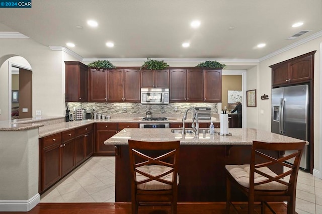 kitchen with light tile patterned floors, kitchen peninsula, a breakfast bar area, appliances with stainless steel finishes, and decorative backsplash