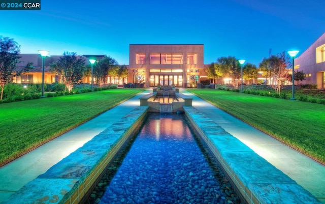 pool at dusk featuring a lawn