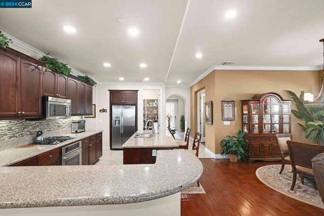 kitchen with light stone countertops, sink, stainless steel appliances, and a kitchen island with sink