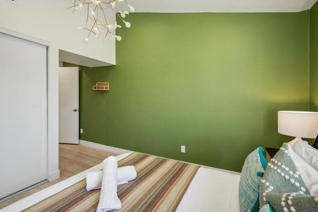 bedroom with hardwood / wood-style flooring, an inviting chandelier, lofted ceiling, and a closet