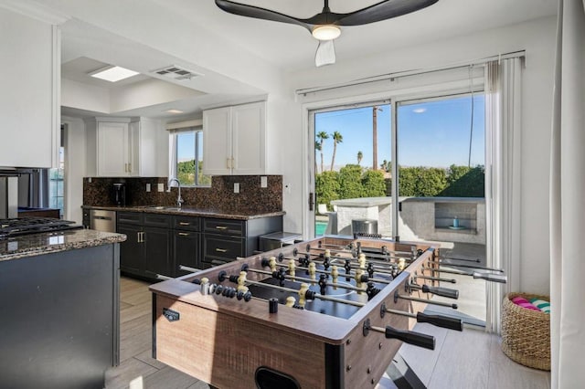 kitchen featuring backsplash, white cabinetry, a wealth of natural light, and dark stone countertops