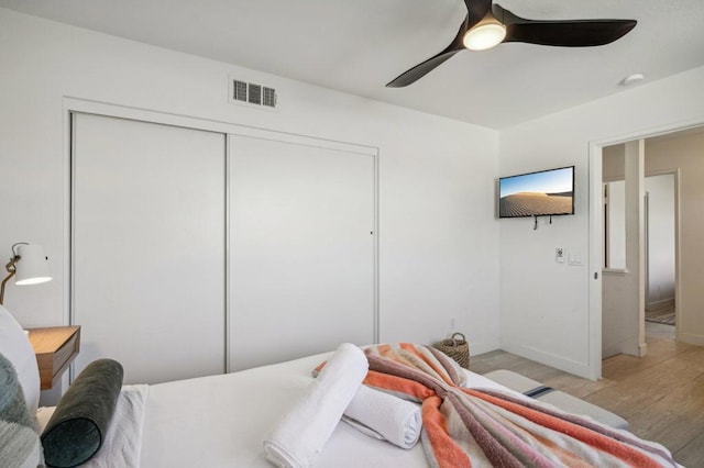 bedroom featuring a closet, light hardwood / wood-style floors, and ceiling fan