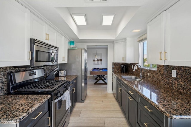 kitchen featuring appliances with stainless steel finishes, a tray ceiling, sink, white cabinets, and pool table