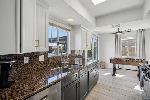 kitchen with white cabinets, ceiling fan, dark stone countertops, and sink