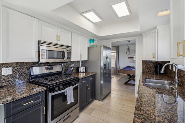 kitchen with appliances with stainless steel finishes, sink, light hardwood / wood-style flooring, white cabinetry, and pool table