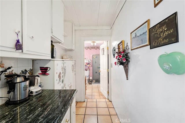 kitchen featuring light tile patterned floors, white cabinetry, and dark stone counters