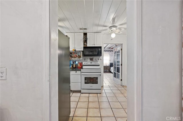 kitchen featuring white cabinets, decorative backsplash, stainless steel fridge, light tile patterned floors, and white electric range oven