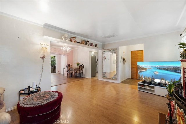 living room featuring wood-type flooring, ornamental molding, and a chandelier