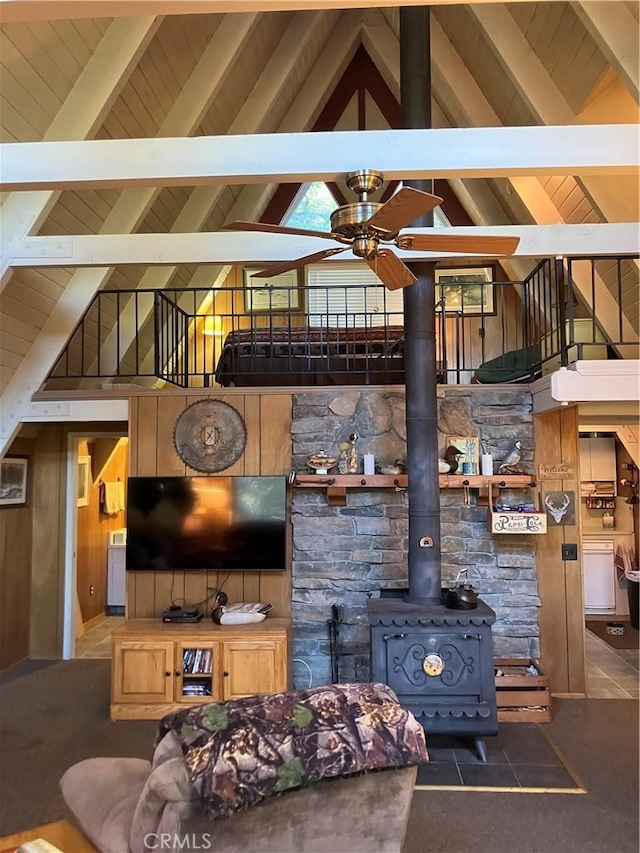 living room featuring beam ceiling, high vaulted ceiling, a wood stove, and ceiling fan