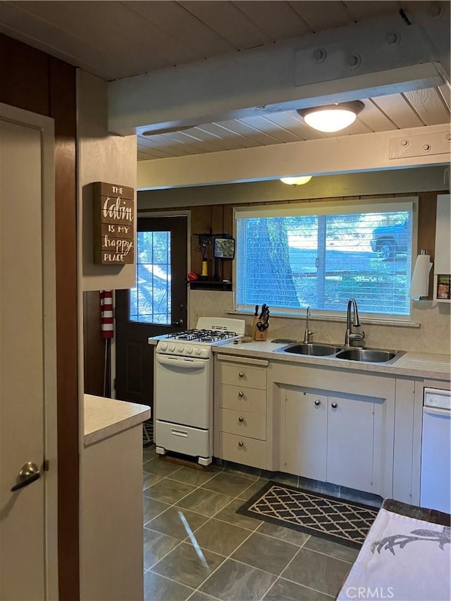 kitchen with sink, backsplash, white range with gas cooktop, white cabinets, and dark tile patterned flooring