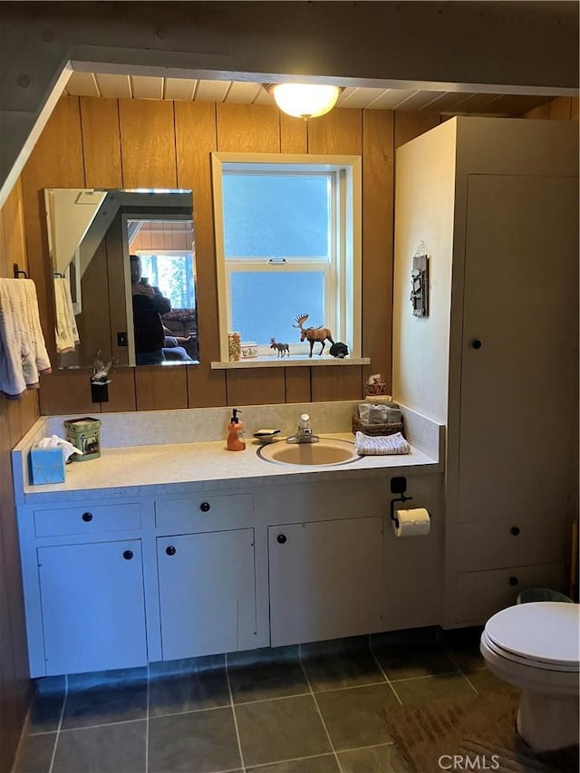 bathroom featuring wooden walls, tile patterned flooring, vanity, and toilet