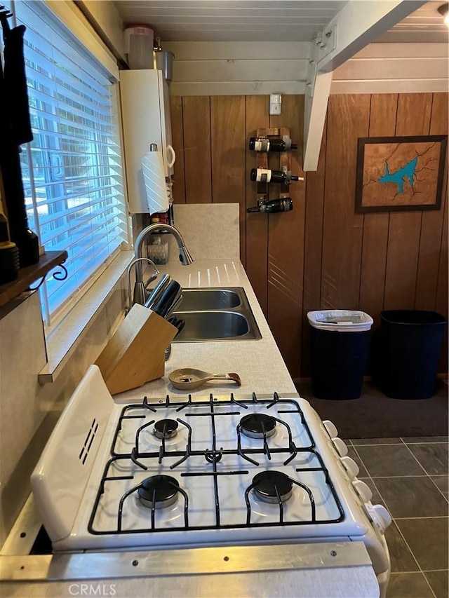 kitchen with white range oven, water heater, wooden walls, and sink