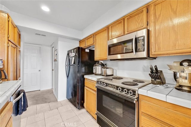 kitchen featuring black appliances, tile counters, and light tile patterned floors