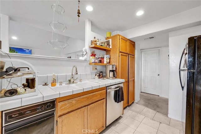 kitchen with light tile patterned floors, sink, tile countertops, and black appliances