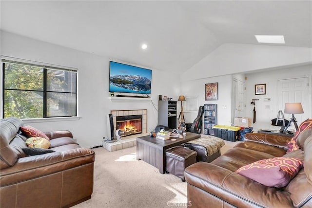 living room with a tile fireplace, carpet floors, and vaulted ceiling with skylight