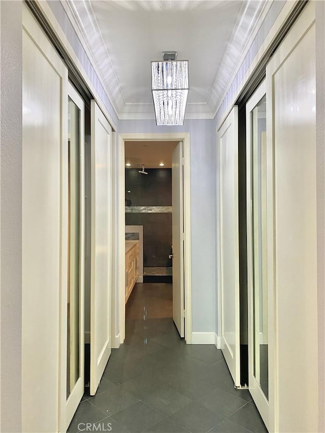 hall with dark tile patterned floors, a notable chandelier, and crown molding