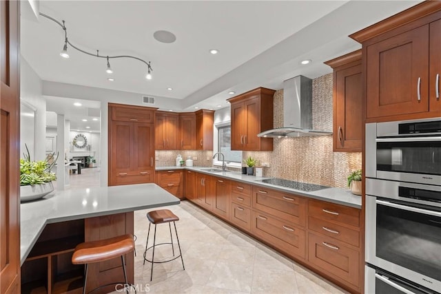 kitchen with decorative backsplash, a breakfast bar area, stovetop, double oven, and wall chimney exhaust hood