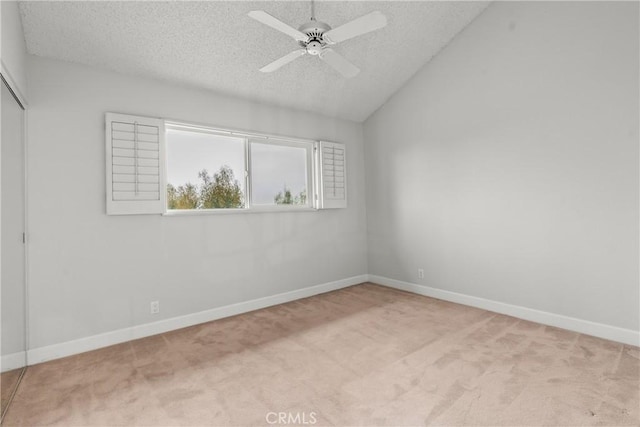 carpeted spare room with vaulted ceiling, ceiling fan, and a textured ceiling