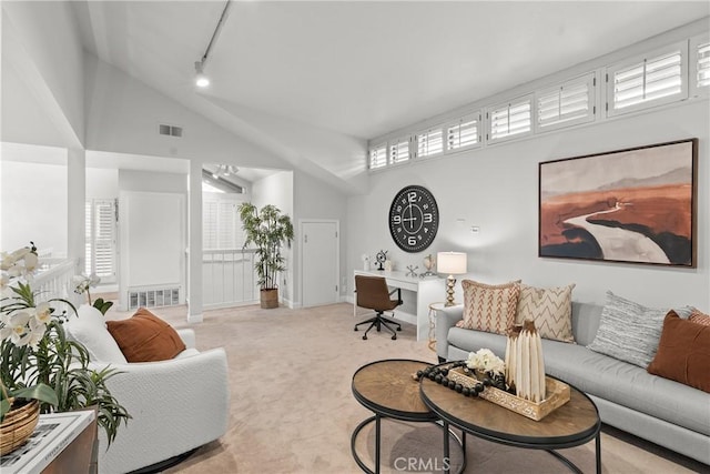 living room featuring a high ceiling, light colored carpet, track lighting, and a healthy amount of sunlight