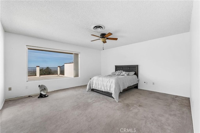 carpeted bedroom featuring ceiling fan and a textured ceiling