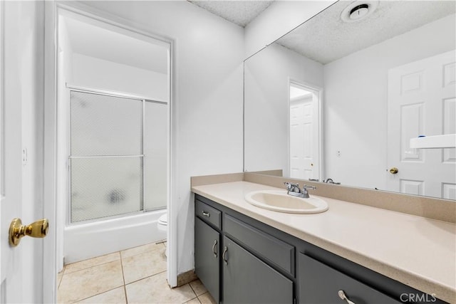 full bathroom featuring enclosed tub / shower combo, tile patterned floors, a textured ceiling, toilet, and vanity