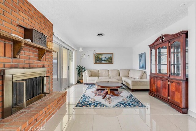 living room featuring light tile patterned floors, a textured ceiling, and a brick fireplace