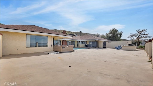 rear view of property with a patio area and a hot tub