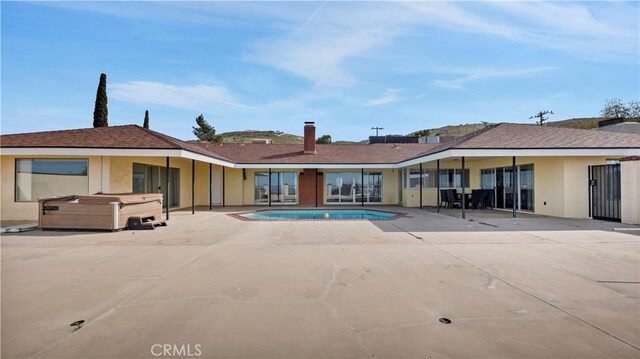 back of house with a patio and a pool with hot tub