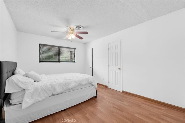 bedroom with hardwood / wood-style floors, a textured ceiling, and ceiling fan