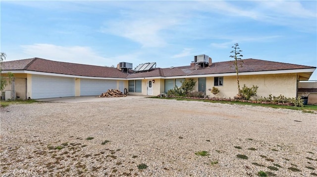 single story home featuring solar panels, a garage, and central AC