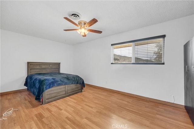 bedroom featuring a textured ceiling, light hardwood / wood-style flooring, and ceiling fan