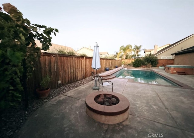 view of swimming pool featuring a hot tub, a patio, and a fire pit