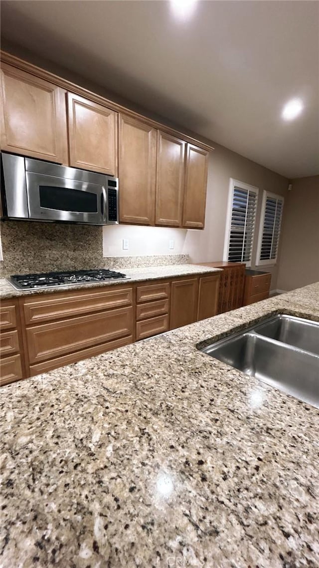 kitchen featuring stainless steel appliances, light stone countertops, and sink