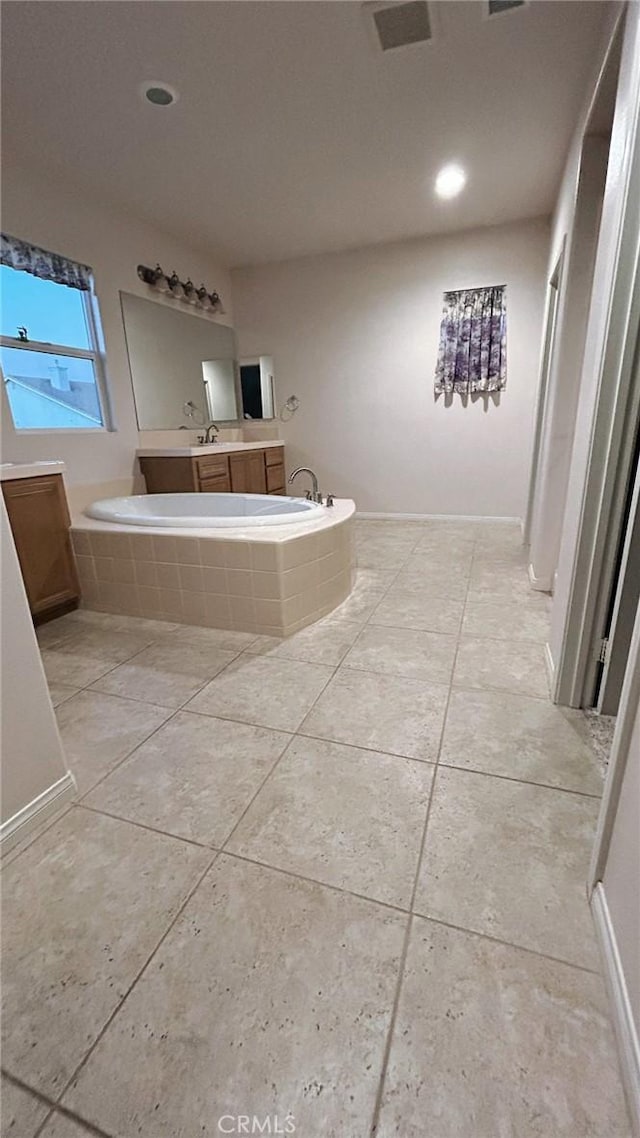 bathroom featuring tile patterned floors, vanity, and a relaxing tiled tub