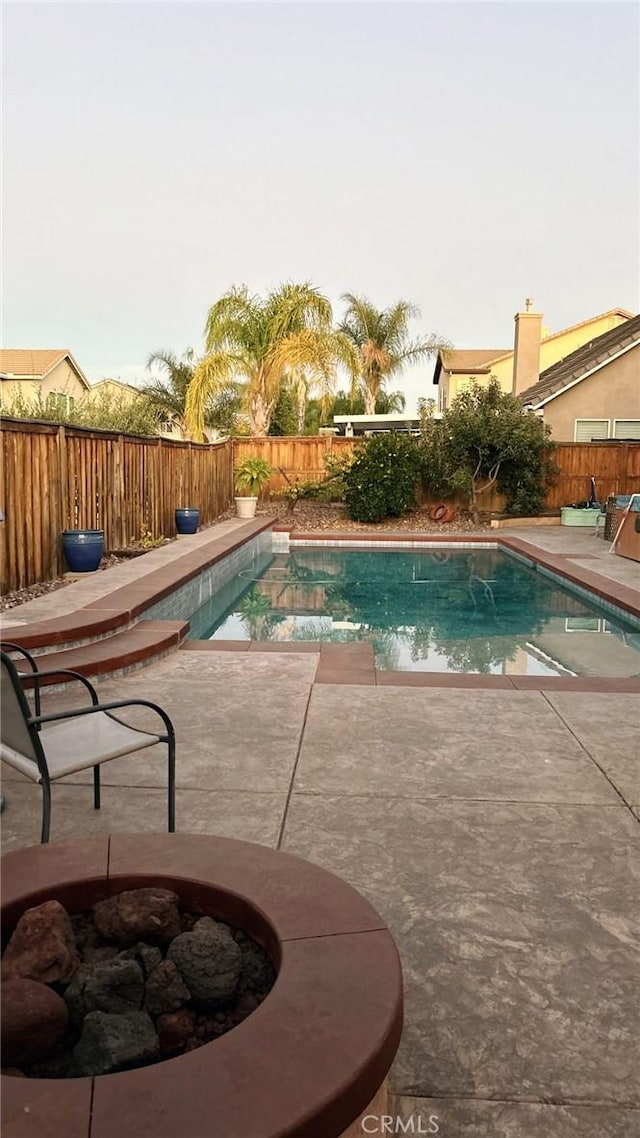 view of swimming pool featuring a patio and a fire pit