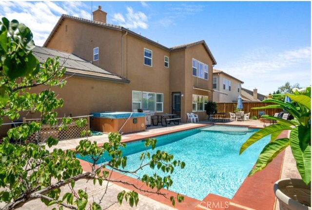 view of swimming pool featuring a patio area and a hot tub