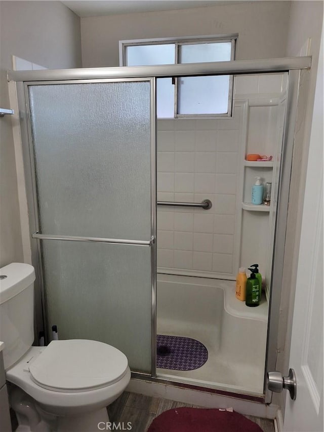 bathroom with a shower with shower door and toilet