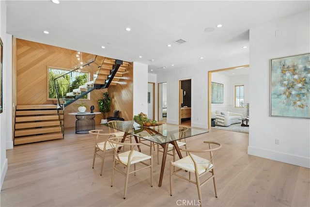 dining space featuring wood walls and light hardwood / wood-style flooring