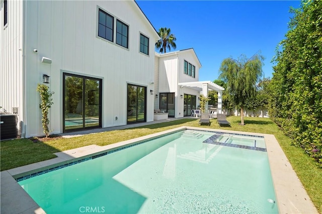 rear view of property with a yard, a pergola, a patio area, and a pool with hot tub