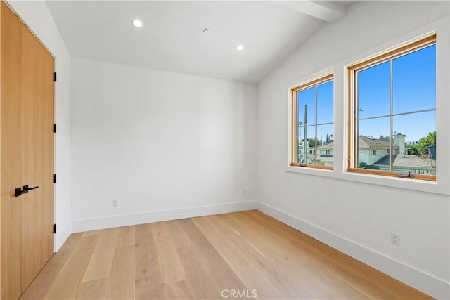 spare room featuring light hardwood / wood-style floors and lofted ceiling