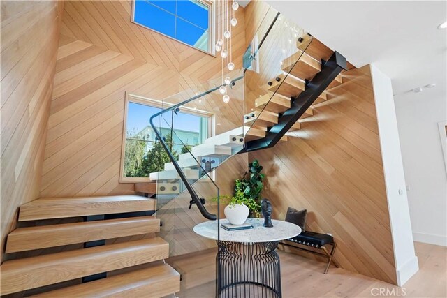 stairs with wooden walls, hardwood / wood-style floors, and a towering ceiling