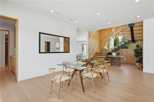 dining room with light wood-type flooring and wooden walls