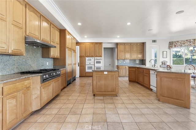 kitchen with sink, a kitchen island, tasteful backsplash, white appliances, and light tile patterned floors