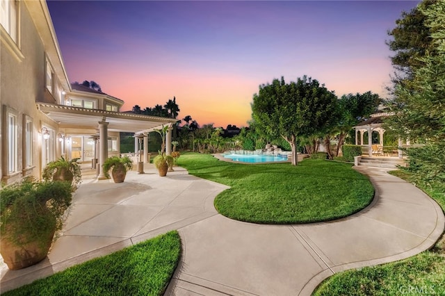 yard at dusk featuring a patio area and ceiling fan