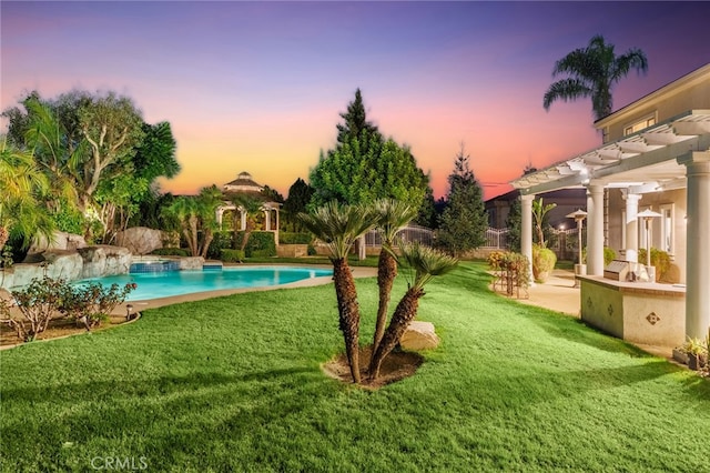 pool at dusk with a pergola and a yard