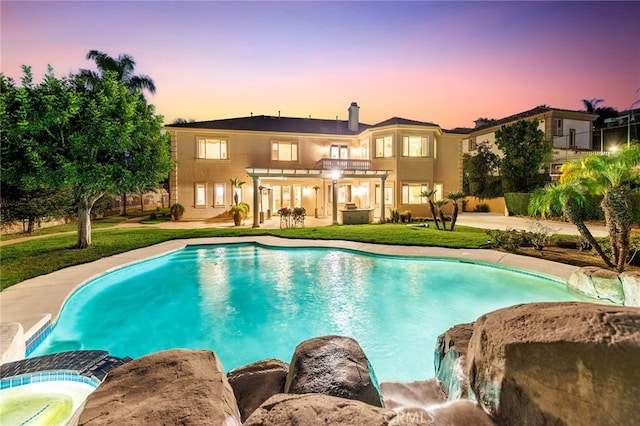 pool at dusk with a patio area and a yard