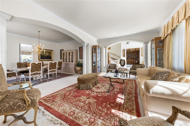 carpeted living room with an inviting chandelier, ornamental molding, and ornate columns