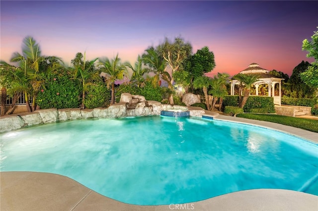 pool at dusk with a gazebo and pool water feature