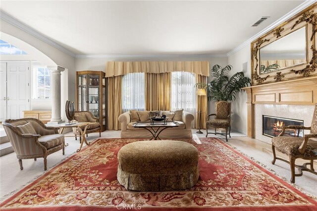 living area with a fireplace, decorative columns, ornamental molding, and light colored carpet