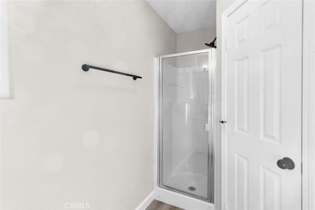 bathroom featuring wood-type flooring and a shower with shower door